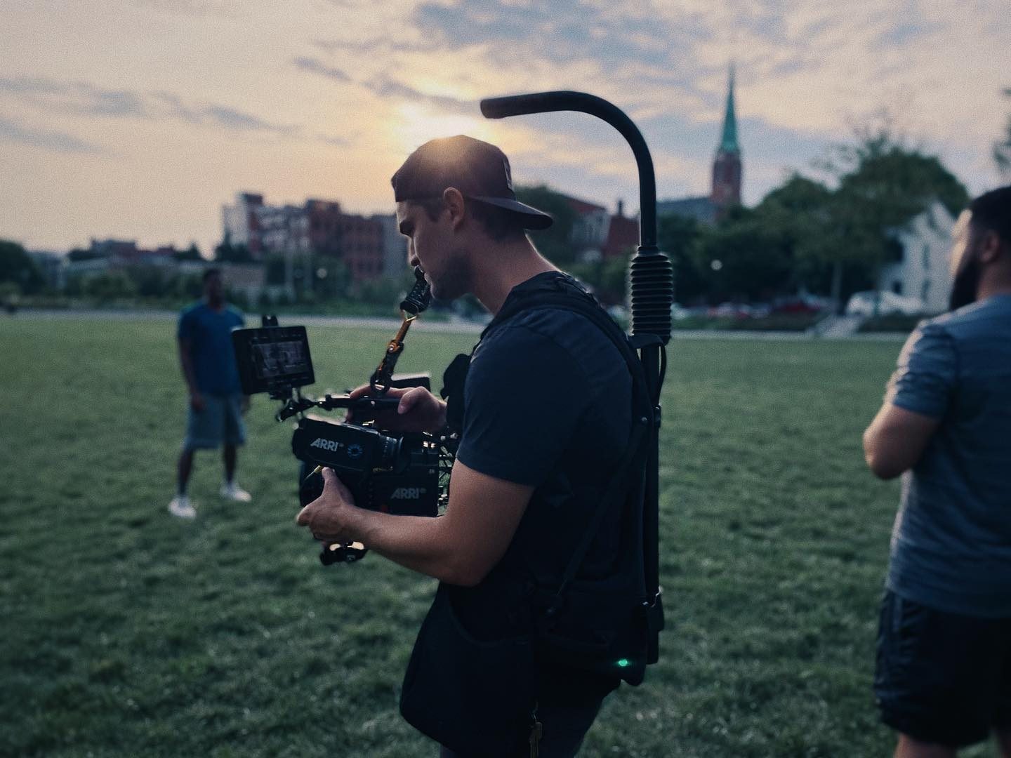 Director of photography operating a handheld camera rig on a dim interior set