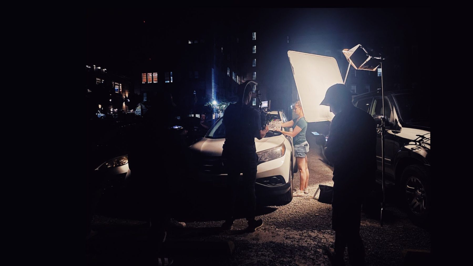 Night exterior production — softbox key light, crew, and cinematographer in silhouette